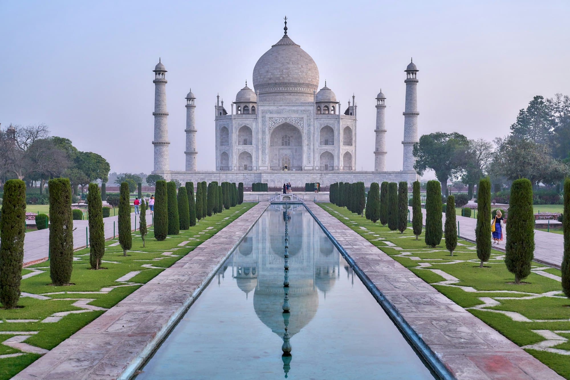 The Taj Mahal reflected in a long pool at sunrise in India